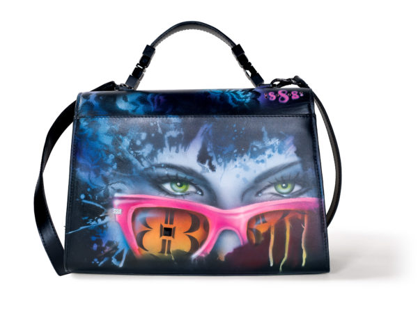 Back view of BABE-Bad Ass Business Exec Satchel in smooth black Italian leather with graffiti artwork of a woman wearing pink frame glasses with BB logo on lenses. Her green eyes peek over frames.