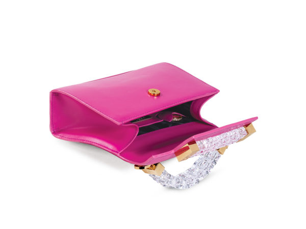 Side angle interior view of fuchsia pink Mini Jewel Top Handle handbag open and on its side. The 22 carat gold plated ‘Promise’ penny is tucked into a fuchsia pink mini pocket in the handbag’s dark interior.