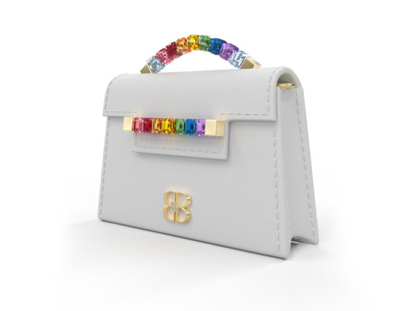 Front side angle view of white Rainbow Baby Jewel Crossbody showing a slender, collapsible side profile. Emerald-cut Swarovski crystals are flush together at their edges, forming a rainbow gradient with square-shaped yellow gold hardware end caps.