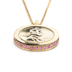 Side view of the Devotion, Wear to Evoke Love pendant and necklace with plated US penny set into a 22 carat band edged with sparkling, Rose Pink-Swarovski crystals.