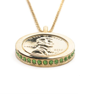 Side view of the Evergreen, Wear to Evoke Healing Energy pendant and necklace with plated US penny set into a 22 carat band edged with sparkling, Fern Green-Swarovski crystals.