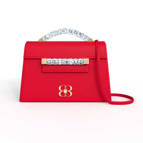 Front view of cherry red Baby Jewel Crossbody bag with a tapered trapezoidal shape, clear Swarovski crystal top handle and front strap, yellow gold hardware, yellow gold and crystal BB plaque, and matching red detachable shoulder strap.